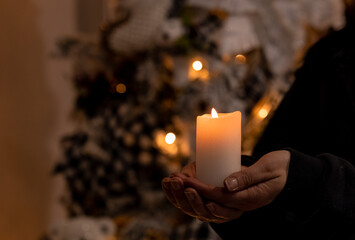 person holding a candle with a christmas tree on the back 