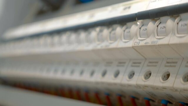 Electrical box with many wires, rows of switches, electrical parts, automatic breakers. Closeup. Follow focus