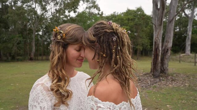 country lesbian brides foreheads together on farm on wedding day