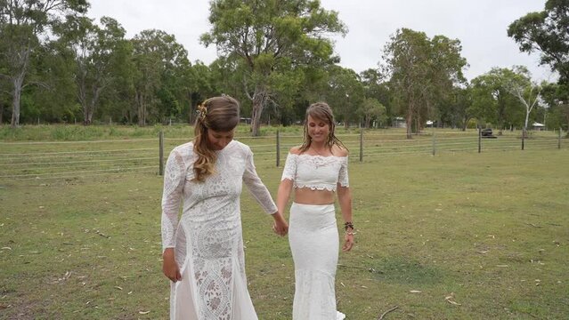 country lesbian brides holding hands and kissing at farm on wedding day