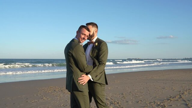 gay groom couple dancing on beach on wedding day