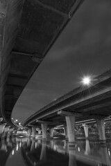 Underside of an elevated road across river at dusk