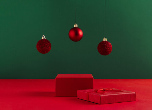 Creative Christmas concept made of podium and red baubles on bold green background. Minimal New Year advertisement concept. Mock up showcase for product, promotion, sale or presentation.