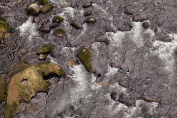Looking down at river rapids washing over rocks
