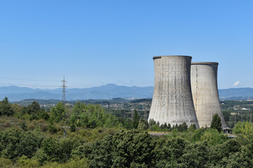 Central eléctrica produce energía, de fondo montañas y paisaje verde con un cielo azul claro. ...
