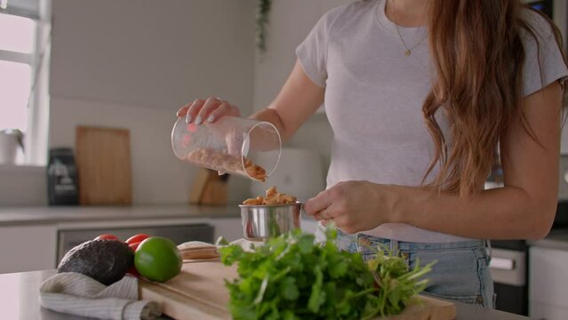 Female cook measuring cashews, preparing meal