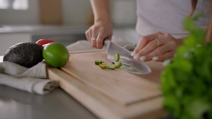 Female hands cut jalapeno on cutting board in kitchen, chop, cooking food