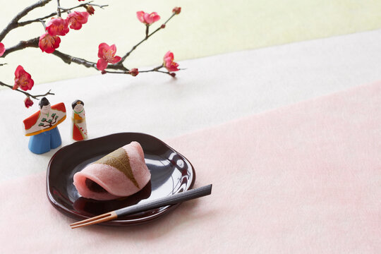3色の和紙の上の桜餅と梅と雛人形
