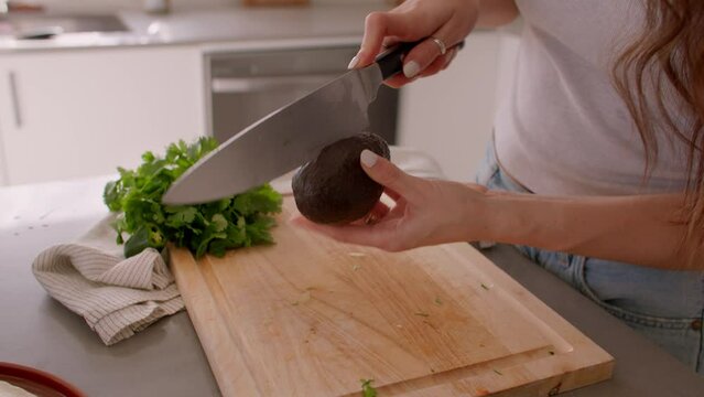 Hands cut avocado on cutting board in kitchen, chop, cooking food
