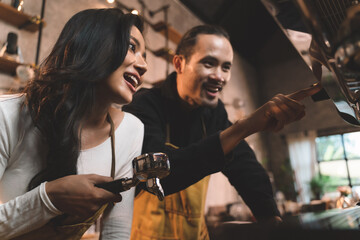 portraits of happiness two waiter teaching woman with apron to use a coffee machine for make a...