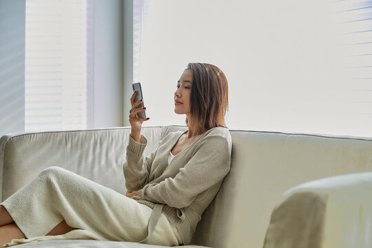 ソファでスマホを見る30代女性