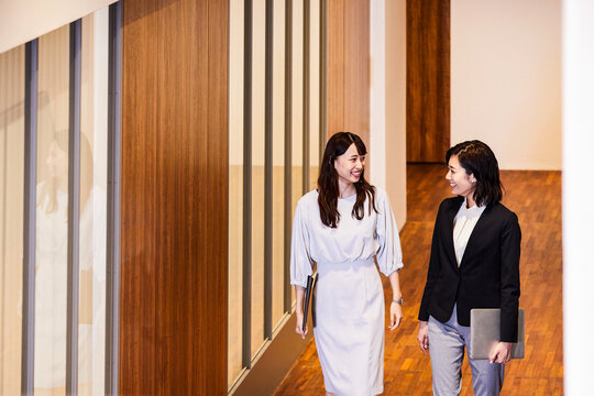 オフィスを会話しながら歩くビジネスウーマン