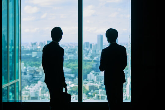 窓の外を見ながら会話するビジネスマン