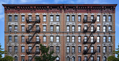 Old fashioned New York City apartment building with decorative roof cornice and external fire escapes