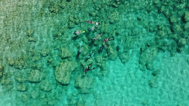 Group of SCUBA divers and snorkelers in clear shallows of Pefkos, Rhodes; aerial