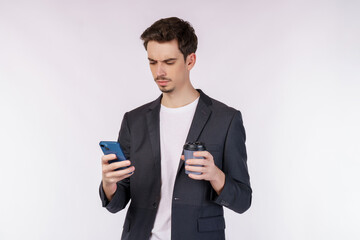 Portrait of a happy businessman using smartphone and holding hot coffee over white