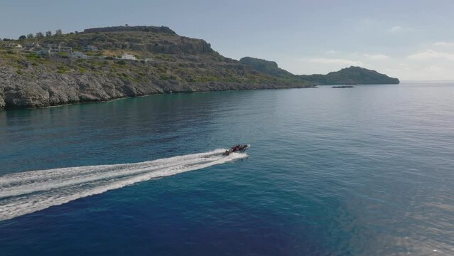 Inflatable with outboard taking divers out along Rhodes island coastline; aerial