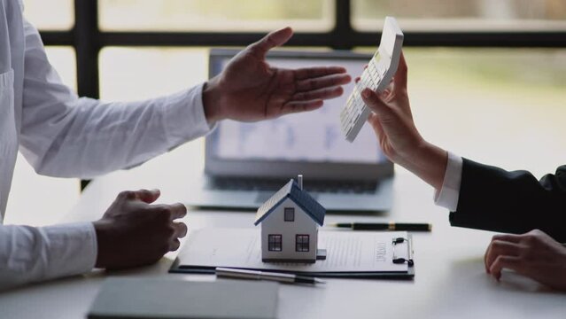 Close up of business's hands selling and signing agreement paperwork for loan financial to buying the house properties then give a key to customers.