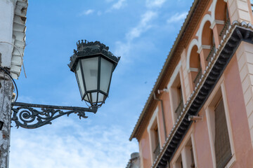 Fototapeta na wymiar A metal street light hanging outside of a house in a narrow street