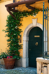 Fototapeta na wymiar Beautiful entrance to the italian villa with the green climbing plants on the walls around it in the old town of Varenna, Lombardy, Italy.