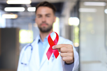 Man doctor holding a red ribbon in his hand for december world aids day, an international day of...