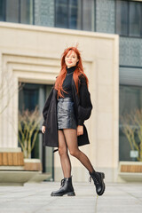 Young woman with red hair walking along the street