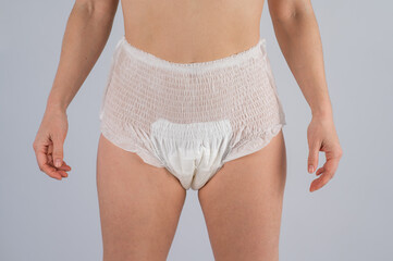 Woman in adult diapers on a white background. Incontinence problem.