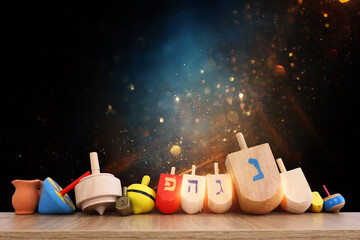 Image of jewish holiday Hanukkah with wooden dreidels collection (spinning top) over glitter...