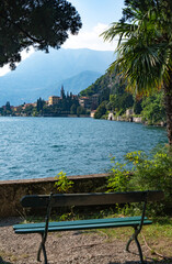 The bench in the botanical garden of Villa Monastero overlooking Lake Como, picturesque town of Varenna and Alpine Mountains , Province of Lecco, Italy.