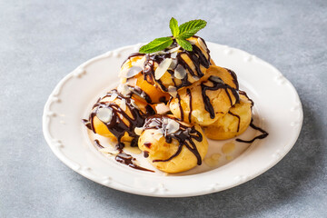 Delicious profiteroles with chocolate and white plate.