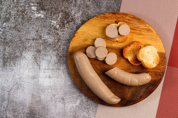 Liver sausage - liverwurst with bread toast on a round wooden cutting board on a dark grey background. Top view, flat lay