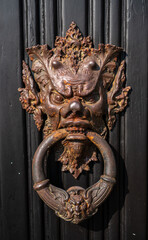 Fascinating door knocker in the shape of head on one of the entrance doors to the historic Villa Monastero, the villa of lords, Varenna, Province of Lecco, Italy.