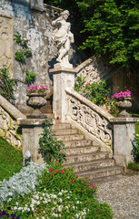 Beautiful ancient sculpture in the botanical garden of the famous historic Villa Monastero, located in traditional village of Varenna, Province of Lecco, on the shore of Lake Como, Italy.