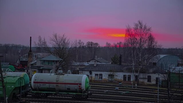 Timelapse of dramatic sunset over Bahnhof (train station), oil tank cars standing still in the backyard, Germany