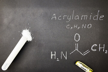 a test tube with acrylamide on a black background a fountain pen and the chemical formula of acrylamide