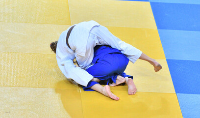 Fighter girls in judogi compete in judo on the tatami