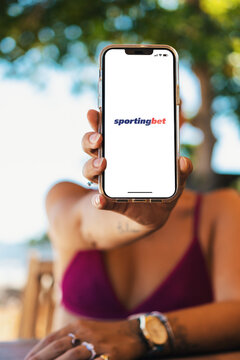 Girl on the beach holding a smartphone with Sportingbet betting provider app on the screen. Rio de Janeiro, RJ, Brazil. November 2022