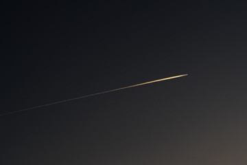Dawn evening the plane draws a line across the sky