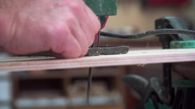 Artisan luthier using a DIY electric jigsaw power tool to cut circle in wood