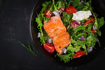 Roasted salmon fish fillet and fresh green lettuce vegetable tomato salad with cream cheese. Top...