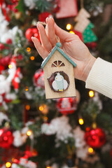 Christmas owl toy in hands. Christmas, New Year interior with garland, red and gold balls on a fur tree background