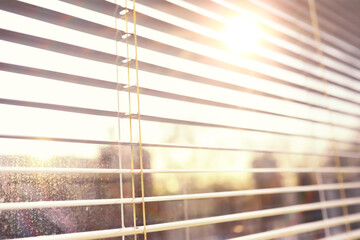 Background the sun shines in the spring through the metal blinds on the window. The texture of the...