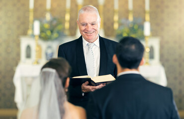 Wedding, priest and couple at the altar saying vows while getting married in a church for...