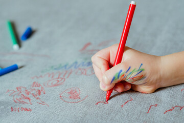 A child's smeared with ink hand, drawing with a red marker on the upholstery of the couch....