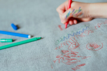 Kid freehand drawing red felt-tip pen on the upholstery of the couch. Furniture fabric. Cleaning...