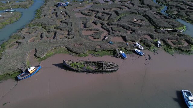 Mooring Boats And Shipwreck At Marshes In Tollesbury Marina, Essex, United Kingdom. Aerial Tilt-down