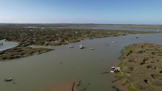 Yacht Sailing Across The River Blackwater With Salt Marshes In Tollesbury Marina, Essex, United Kingdom. Aerial Shot