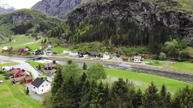 Aerial: flying over the Fl&aring;m valley among mountains, houses, rivers and green meadows