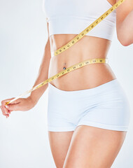 Body, tape measure and diet with a woman measuring her waist to track weightloss in studio on a...