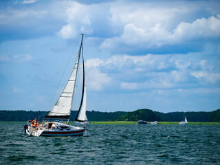 Sailboat sailing on a lake in a windy sunny summer day - obrazy, fototapety, plakaty
